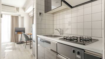 A modern kitchen with a gas stove, stainless steel appliances, and a large window.