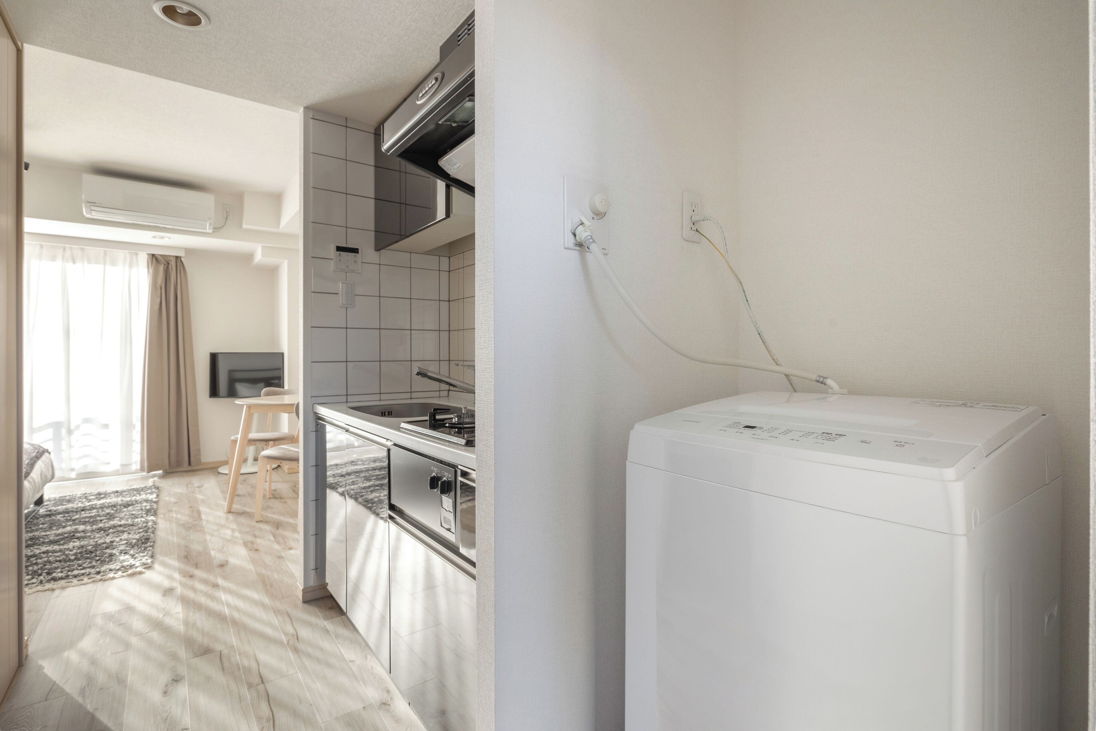A modern kitchen with a built-in oven, a washing machine, and a dining area with a table and chairs.