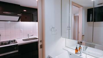 A modern bathroom with a large mirror, a white sink, and a dark-toned cabinet.