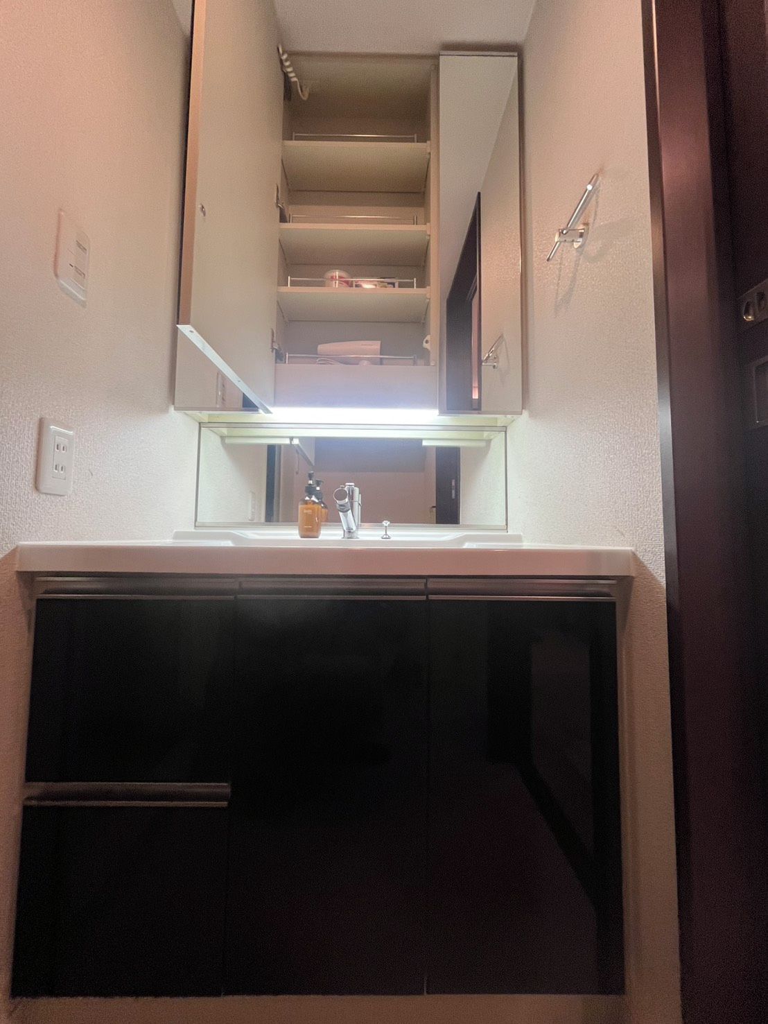 A bathroom with a mirror, sink, and a towel rack.