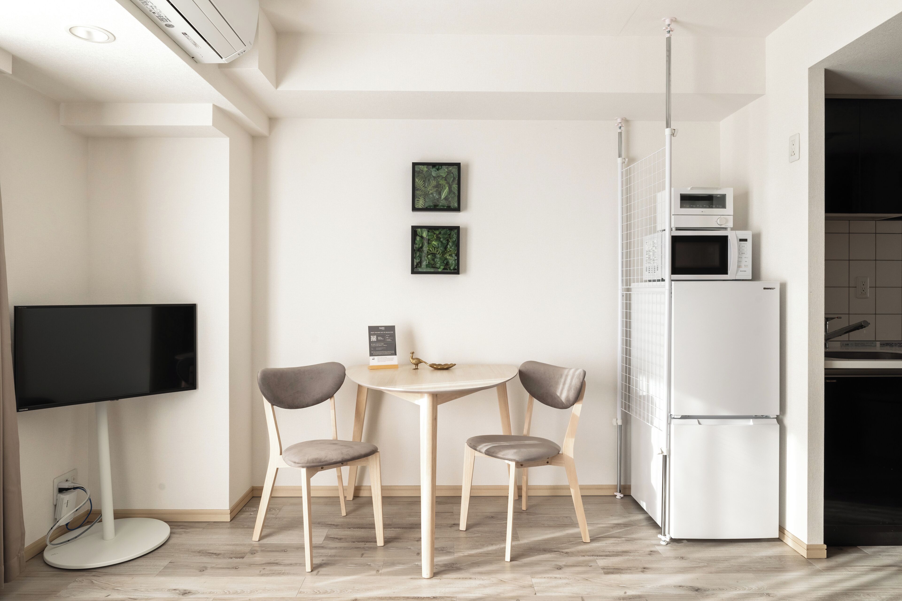 Una cocina moderna con una mesa de comedor, sillas, un televisor de pantalla plana y un refrigerador.