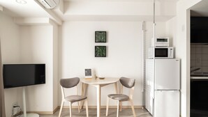 A modern kitchen with a dining table, chairs, a flat-screen TV, and a refrigerator. - Dash Living Ryogoku (Sumida City)