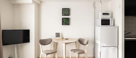 Une cuisine moderne équipée d’une table à manger, de chaises, d’un téléviseur à écran plat et d’un réfrigérateur.