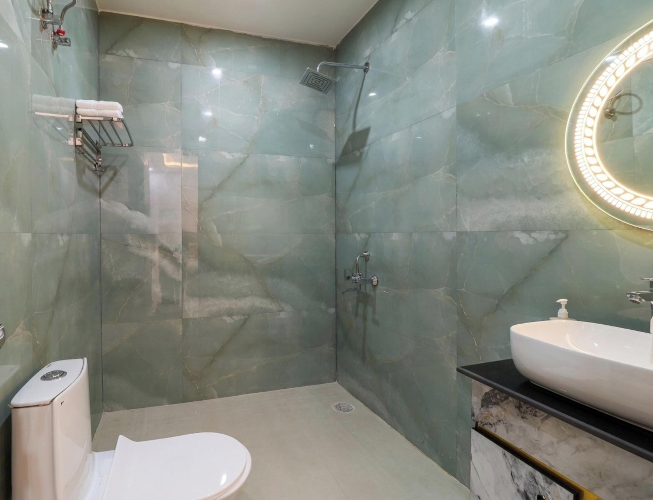 A bathroom with a shower, toilet, sink, and marble walls.