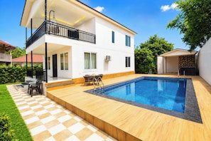 A modern two-story house with a swimming pool, a balcony, and a patio area with outdoor furniture. - 4 Bedroom Farmhouse With Private Pool In Noida (Nodia)