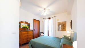 Ein Schlafzimmer mit Bett, Kommode, Stuhl und Deckenventilator.