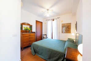 Ein Schlafzimmer mit Bett, Kommode, Stuhl und Deckenventilator.
