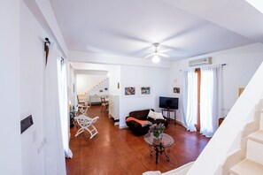 Ein Wohnzimmer mit Sofa, Fernseher und Treppe.