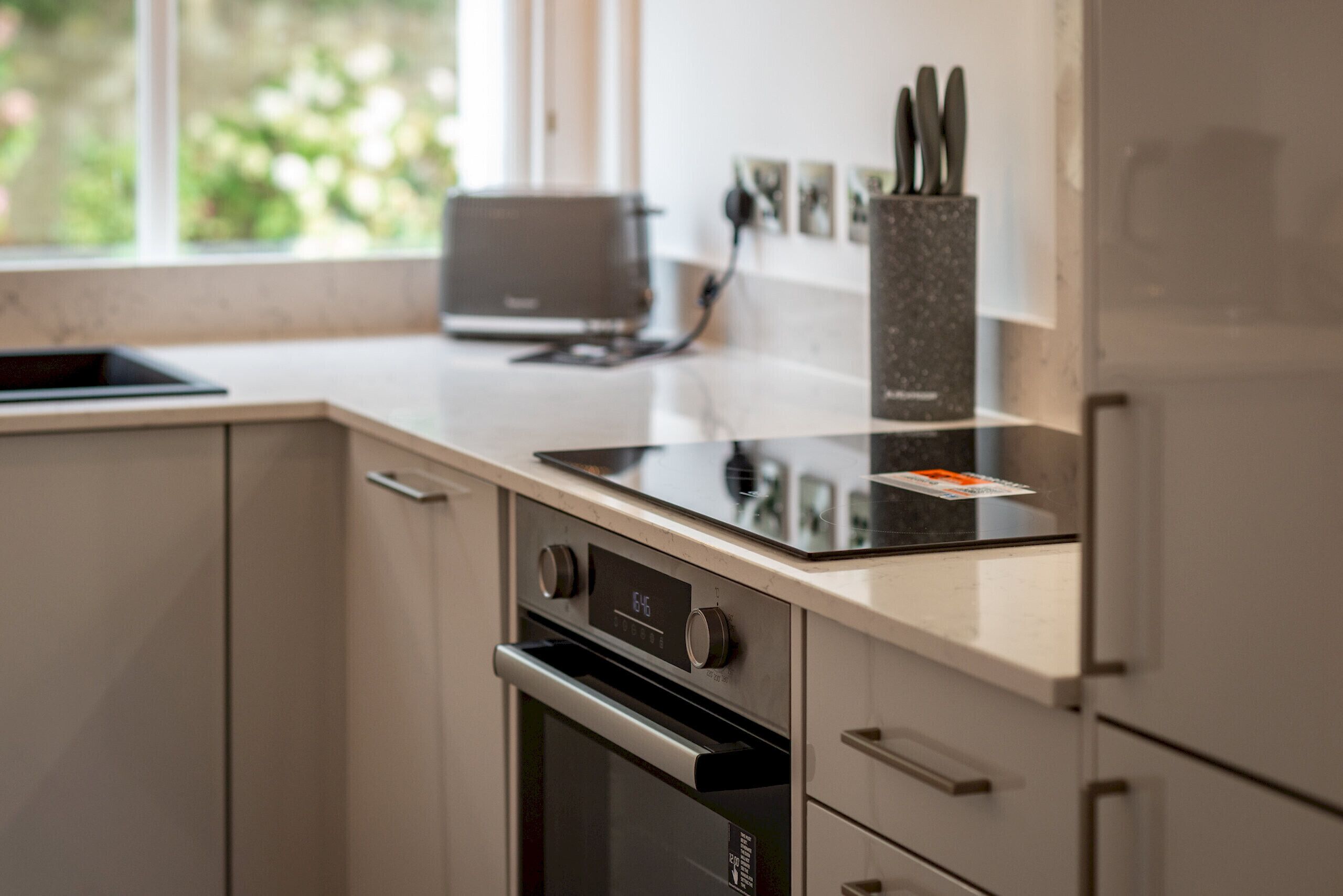 A kitchen with a built-in oven, a toaster, and a knife holder on the countertop.