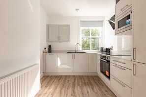 Eine moderne Küche mit weißen Schränken, einem Fenster und einem eingebauten Backofen.