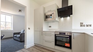 Eine moderne Küche mit integrierten Geräten, ein graues Sofa und ein Fenster mit Blick.