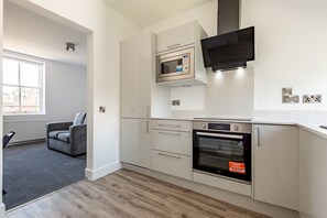 Eine moderne Küche mit integrierten Geräten, ein graues Sofa und ein Fenster mit Blick.