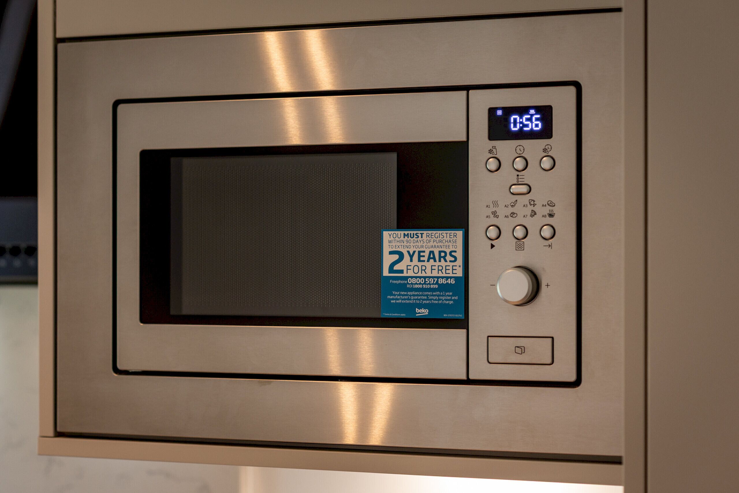 A microwave oven with a digital display, a keypad, and a registration sticker.