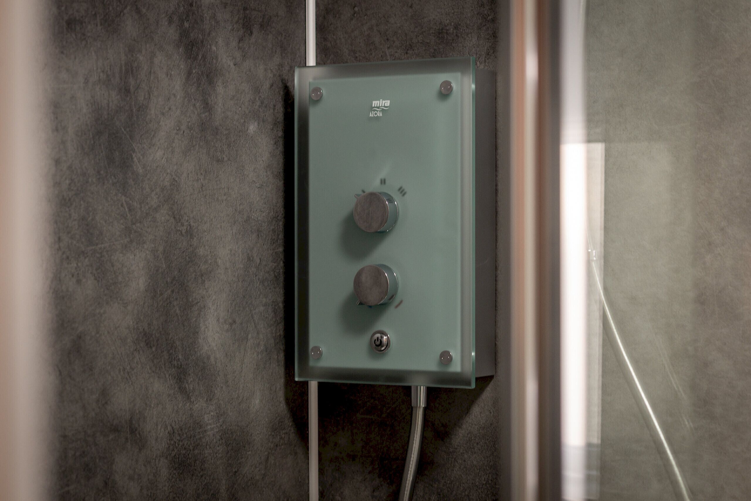 Une boîte électrique métallique dotée de deux boutons et d’une étiquette, fixée à un mur texturé.