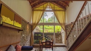 Una habitación acogedora con pared de piedra, un banco de madera, una mesa de comedor con sillas y una escalera.