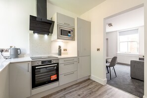 Eine moderne Küche mit eingebauten Geräten, ein Essbereich mit grauem Sofa und ein Fenster für natürliches Licht.