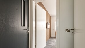 Un couloir avec un mur sombre, une porte blanche et un mur recouvert de panneaux en bois.