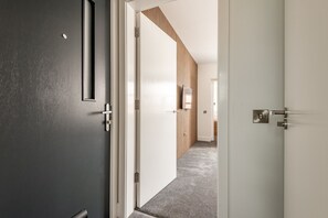 Ein Flur mit einer dunklen Wand, einer weißen Tür und einer Wandverkleidung aus Holz.