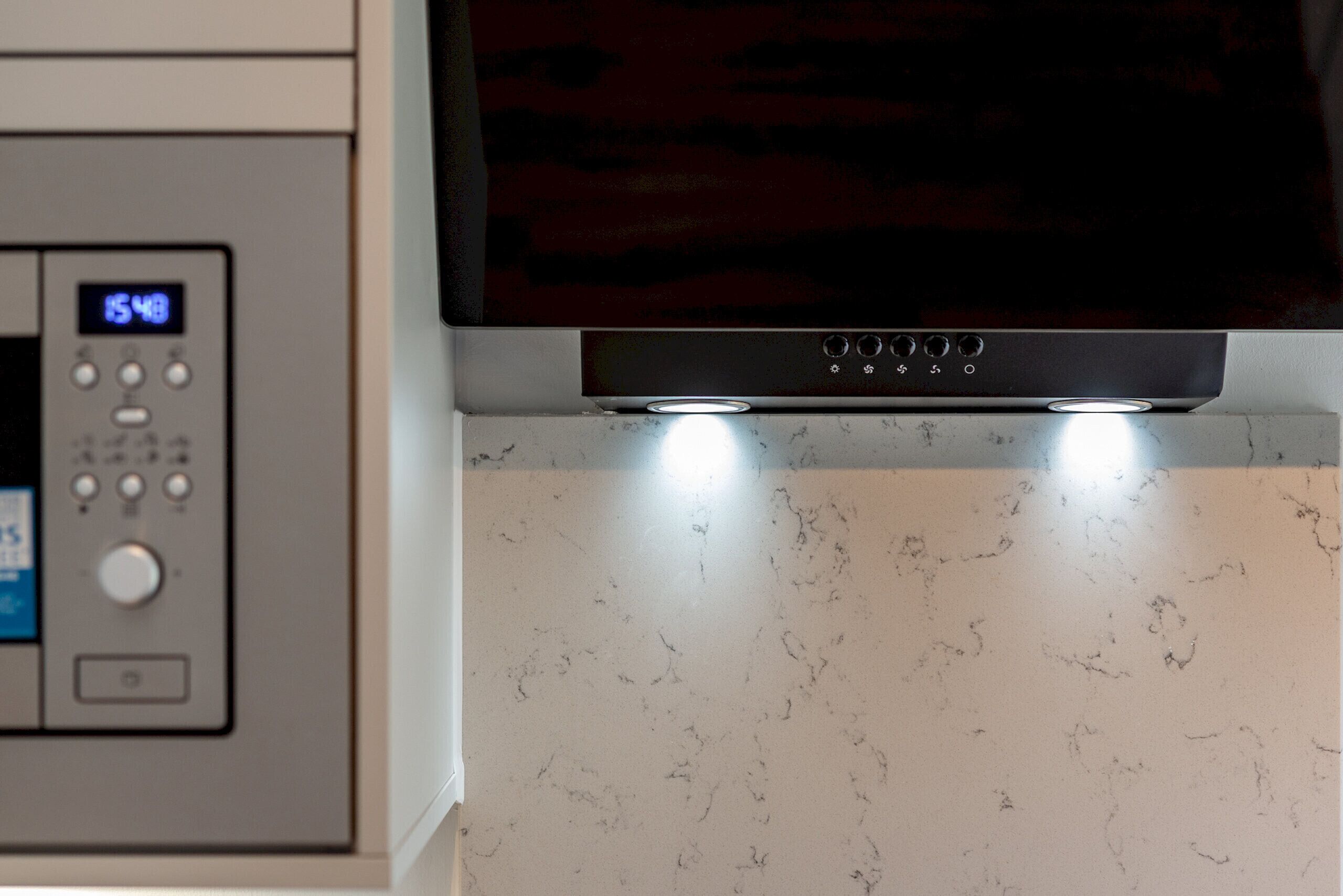 A kitchen with a microwave, oven, and a digital display.