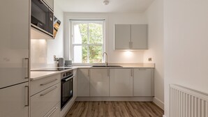 Eine moderne Küche mit weißen Schränken, einer Bosch-Mikrowelle, einem Backofen mit zwei Ebenen und einem Fenster, das für natürliches Licht sorgt.