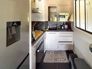 A compact kitchen with white cabinets, a microwave, a coffee maker, and a patterned rug.