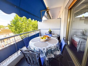 Un balcon avec une table, des chaises et un auvent bleu.