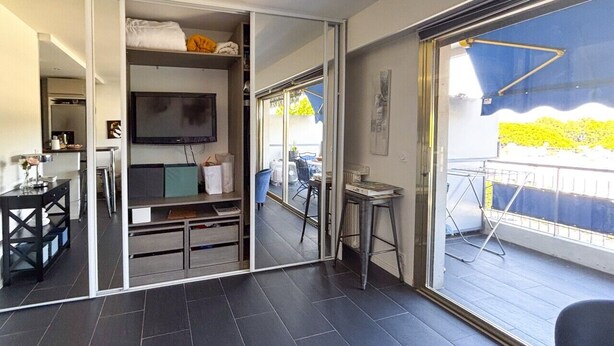 Un interior moderno con un ventanal corredero que da a un balcón, un televisor de pantalla plana y una zona de comedor.
