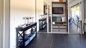 Un interior moderno con zona de comedor, televisor montado en la pared y vistas a través de una puerta de cristal.