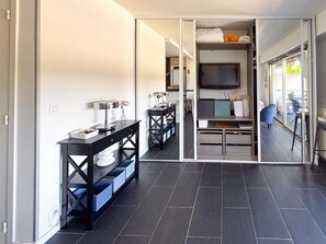 A modern interior with a dining area, a TV mounted on a wall, and a view through a glass door.