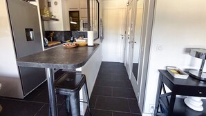Una cocina moderna con encimera oscura, electrodomésticos de acero inoxidable y un taburete negro.