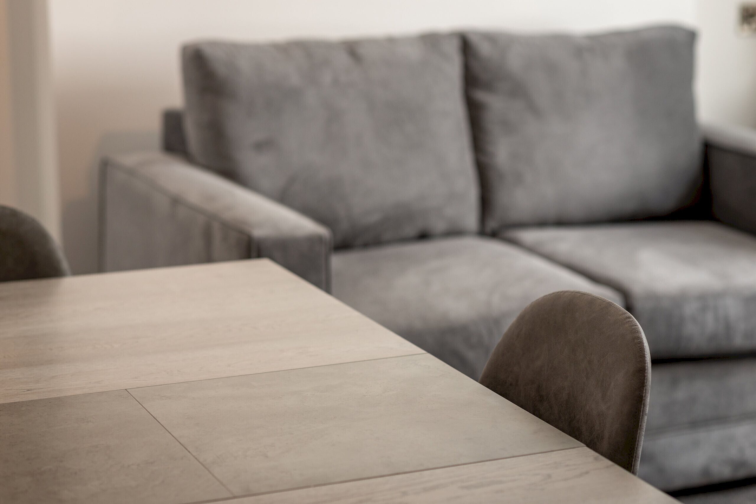 Un salon moderne avec un canapé gris, une table basse en bois et un fauteuil.