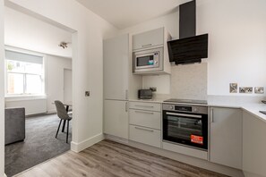 Eine moderne Küche mit weißen Schränken, einer Mikrowelle, einem Toaster und einem Backofen.