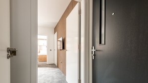Un pasillo con revestimiento de listones de madera, una puerta oscura y suelo alfombrado.