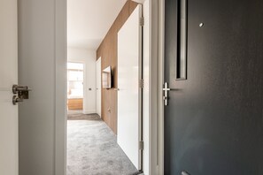 Ein Korridor mit einer Wand aus Holzlatten, einer dunklen Tür und einem Teppichboden.