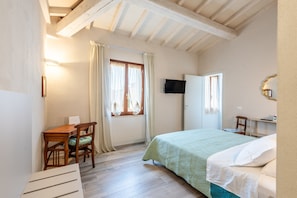 A bedroom with a bed, a desk, a chair, a television, and a window with curtains. - Il Cappero Apartment in the Center of Buonconvento (Buonconvento)