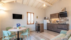 Una cocina moderna con microondas integrado, techo de madera y comedor con mesa redonda y sillas.