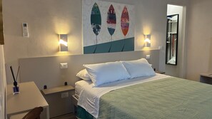 Une chambre d’hôtel comprenant un lit, des tables de chevet, une petite table, une lampe fixée au mur et un tableau.