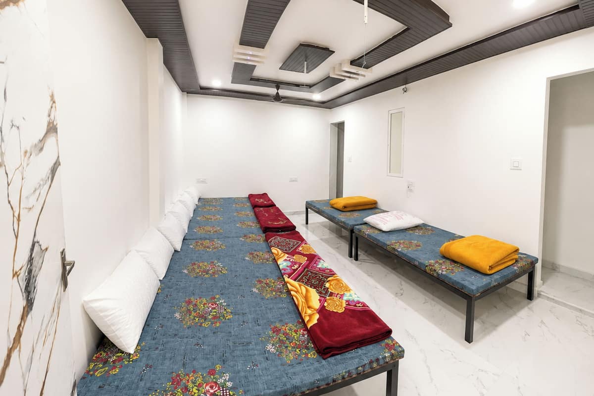 A hotel room with a long bed, two single beds, a marble floor, and a modern ceiling design.