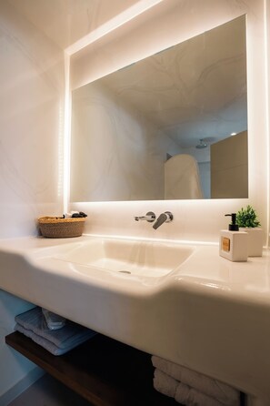 Een badkamer met een wit wastafelmeubel, een spiegel, een handdoekhouder en een kleine plant.