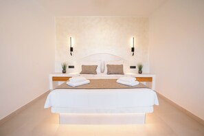 Een moderne hotelkamer met een groot bed, twee nachtkastjes met lampen en een wandlamp.