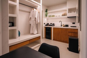 A modern kitchen with built-in appliances, wooden cabinets, and a black trash bin. - Serenity Collection Suites (Santorini)