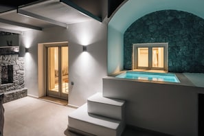 A modern interior with a stone wall, a glass door leading to a balcony, and a built-in hot tub.