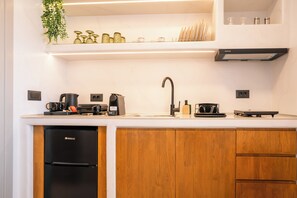 Une cuisine équipée d’un lave-vaisselle, d’une machine à café, d’une bouilloire et d’un évier.