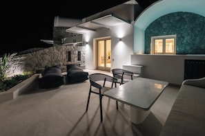 An outdoor patio with a stone wall, a table, and chairs.