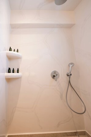 A bathroom with a shower, a toilet, and a shelf with toiletries.