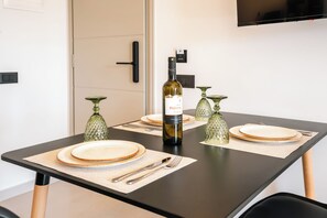 A dining table with placemats, plates, cutlery, and a bottle of wine. - Serenity Collection Suites (Santorini)