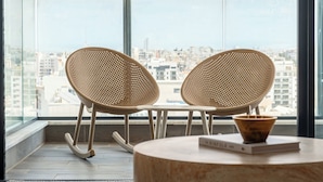 Un balcon avec deux fauteuils en osier et une petite table sur laquelle se trouvent un livre et un bol.