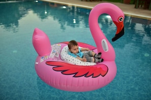 A child on a pink flamingo float in a pool.