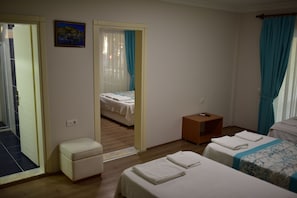 A hotel room with two beds, a small seating area, and a view through an open door.