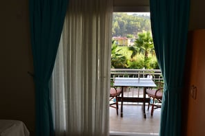 A room with a view of a balcony, a table, and chairs.